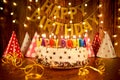 Happy birthday cake with candles on the background of garlands a Royalty Free Stock Photo