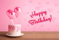 Happy Birthday cake with pink heart shaped balloons on wooden table over pink background Royalty Free Stock Photo