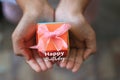 Happy Birthday card greeting with small orange gift box in hand. Birthday surprise concept with a gift of origami paper craft