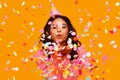 Happy birthday! cheerful funny ethnic woman with festive confetti on yellow