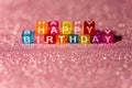 Happy Birthday with colored blocks letters on pink glitter backgrounds. Postcard to celebrate. Copy space