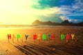 Happy birthday colorful candles on beach sunrise.