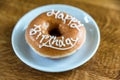 Happy birthday donut on white dessert plate on wooden table