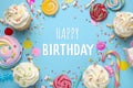 Happy Birthday! Flat lay composition with cupcakes on light blue background Royalty Free Stock Photo
