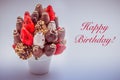 Happy birthday greeting card with red lettering; A bundle of edible flowers, arrangement of strawberries covered with chocolate