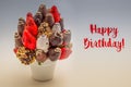 Happy birthday greeting card with red lettering; A bundle of edible flowers, arrangement of strawberries covered with chocolate