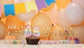 Happy birthday greetings for the year 65 from golden letters of candles burning against the background of mine space balloons. Royalty Free Stock Photo