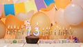 Happy birthday greetings for 73 years from gold letters of candles burning against the background of mine space balloons. Royalty Free Stock Photo