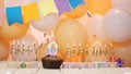 Happy birthday greetings for 0 years from gold letters of candles burning against the background of mine space balloons. Royalty Free Stock Photo