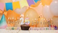 Happy birthday greetings for 25 years from gold letters of candles burning against the background of mine space balloons. Royalty Free Stock Photo