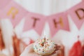 Happy Birthday. Hand holding delicious birthday donut with candle in room with pink garland Royalty Free Stock Photo