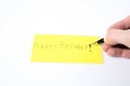 Happy birthday handwrite with a pen and a hand on a yellow paper