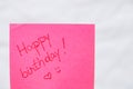 Happy birthday handwriting text close up isolated on pink paper with copy space. Writing text on memo post reminder Royalty Free Stock Photo