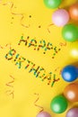 Happy birthday letters from candies. Birthday background. Colorful balloons and candies on yellow table Royalty Free Stock Photo