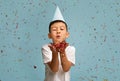 Happy Birthday. Little Asian Boy Wearing B-Day Hat Blowing Confetti At Camera Royalty Free Stock Photo