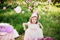 Happy birthday little girl making wish blowing candles on cake with pink decor in beautiful garden Royalty Free Stock Photo