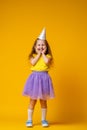 Happy Birthday! little girl in festive hat on her birthday on yellow background Royalty Free Stock Photo