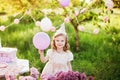 Happy birthday little girl making wish blowing candles on cake with pink decor in beautiful garden Royalty Free Stock Photo