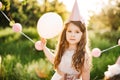 Happy birthday little girl making wish blowing candles on cake with pink decor in beautiful garden Royalty Free Stock Photo