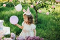 Happy birthday little girl making wish blowing candles on cake with pink decor in beautiful garden Royalty Free Stock Photo