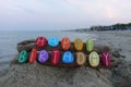 Happy Birthday message with multi colored stones over two pieces of wood with sea background Royalty Free Stock Photo