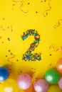 Happy Birthday number 2 made of candies with colorful balloons on yellow background Royalty Free Stock Photo