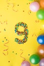 Happy Birthday number 9 made of candies with colorful balloons on yellow background Royalty Free Stock Photo