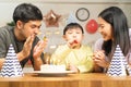 Happy birthday party in family, asian young parent father, mother and little cute boy or child celebrating, blowing candles on the Royalty Free Stock Photo