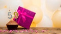 Happy birthday with a pink gift box for a 59 year old woman. Beautiful birthday card with cupcake and burning candle number Royalty Free Stock Photo