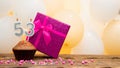 Happy birthday with a pink gift box for a 53 year old woman. Beautiful birthday card with a cupcake and a burning candle number Royalty Free Stock Photo