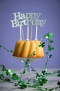 Happy birthday ring cake with clover decoration on marble table and lilac background Royalty Free Stock Photo