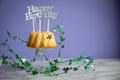 Happy birthday ring cake with clover decoration on marble table and lilac background Royalty Free Stock Photo