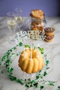 Happy birthday ring cake, cookies, biscuits, muffins and champagne  with clover decoration on marble table and lilac background Royalty Free Stock Photo