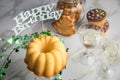 Happy birthday ring cake, cookies, biscuits, muffins and champagne  with clover decoration on marble table and lilac background Royalty Free Stock Photo