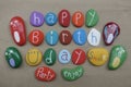 Happy Birthday with a smile and multicolored stones over beach sand Royalty Free Stock Photo