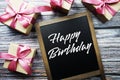 Happy Birthday text on blackboard with gift boxes on wooden background Royalty Free Stock Photo