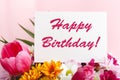 Happy birthday text on card in flower bouquet on pink background. Greeting card in Tulips, daisies, chrysanthemum beautiful spring Royalty Free Stock Photo