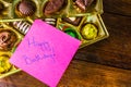 Happy birthday text on memo post reminder, near a golden box with chocolate pralines Royalty Free Stock Photo