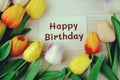 Happy Birthday text message on paper card with tulip flowers bouquet top view on wooden background Royalty Free Stock Photo