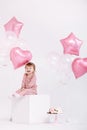 Happy birthday 2 years old little girl in pink dress. white cake with candles and roses. Birthday decorations with white and pink Royalty Free Stock Photo