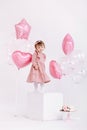 Happy birthday 2 years old little girl in pink dress. white cake with candles and roses. Birthday decorations with white and pink Royalty Free Stock Photo