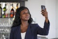 Happy black afro american woman in casual elegant clothes taking selfie portrait photo with mobile phone Royalty Free Stock Photo