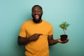 Happy boy indicates a small tree ready to be planted over a light blue color. Concept of forestation, ecology and