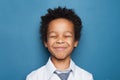 Happy black child boy maks a wish on blue background