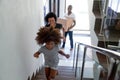 Happy black child running upstairs moving with parents holding boxes Royalty Free Stock Photo