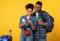 Black Couple Booking Travel Tickets Using Smartphone Over Yellow Background Royalty Free Stock Photo