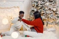 Portrait of happy black couple holding gifts and sitting near Christmas tree Royalty Free Stock Photo