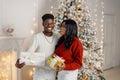 Portrait of happy black couple holding gifts and standing near Christmas tree Royalty Free Stock Photo