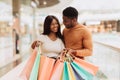 Happy black couple holding shopping bags looking at each other