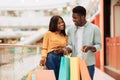 Happy black couple holding shopping bags looking at each other